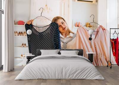 Beautiful woman chooses between two dresses in a clothing store Wall mural