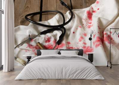 A stethoscope and a bullet lie on a dress with red blood stains, traces of blood on things and a bullet wound, medical assistance Wall mural