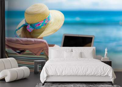 Young woman in straw hat with laptop on the beach. Summer vacation Wall mural