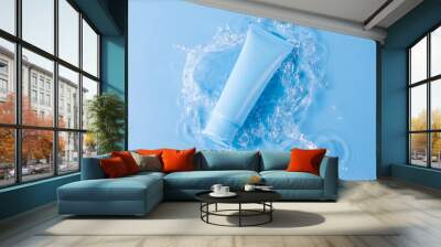 Blank tube of skincare product and splashing water on blue background upper view Wall mural