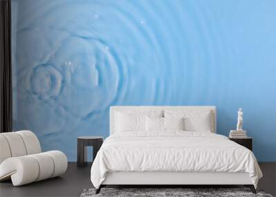 Drops fall down into clear fresh water on light blue background view from above Wall mural