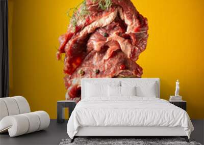 Raw beef meat with spices and dill on a fork before grilling or barbecue. Menu concept for hotel on yellow background. Wall mural