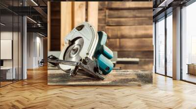 A modern green circular saw lies on a wooden table in the workshop. A close-up of a circular saw Wall mural