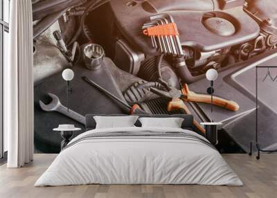 A set of metal spanners, screwdrivers, Pliers and ratchet  of different sizes lies under the hood of the car on an oil cooler. Concept of car repair and tools in car service Wall mural