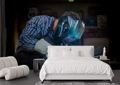 a strong man welder in a black t-shirt, in a welding mask and welders leathers weld metal welding ma Wall mural