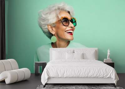 Portrait of a smiling middle-aged Latino-American woman wearing glasses on a green pastel background. Wall mural