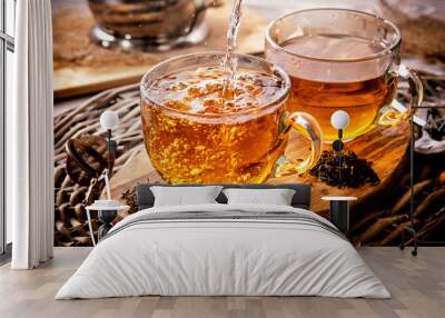 two cups of black tea on a wicker table early in the morning. Tea morning at dawn. The process of pouring tea. Wall mural