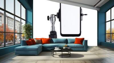 Smartphone mounted on a black tripod in a vertical position on a light isolated background tilted to the right. Wall mural