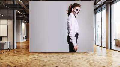 girl in Halloween makeup in the image of a dead man with a white-black skull in a plain shirt with a bow tie Wall mural