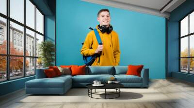 guy with headphones in a yellow sweatshirt on a blue background with a backpack Wall mural