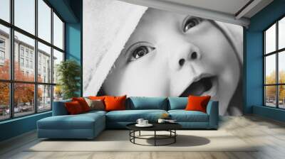 Monochrome portrait of newborn with pure skin playing after bath. Cute smiling baby wearing in towel and looking up at mom. Face of little adorable boy or girl. Wall mural