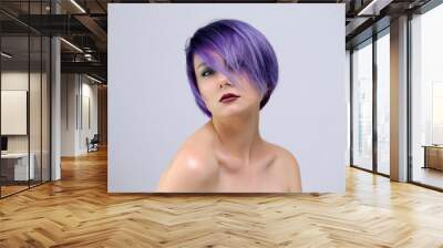 A beautiful, sexy girl with purple hair and a short haircut sits in the middle of the photo with a white background Wall mural