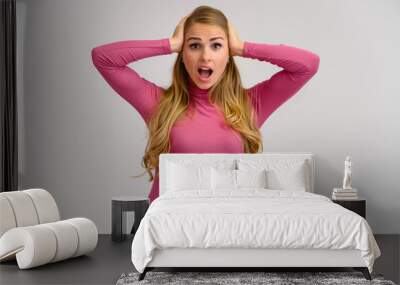 Close-up portrait of a pretty blonde girl with long curly hair standing in the studio on a white background with emotions in different poses in a pink sweater. Beauty, Model, Cosmetics Wall mural