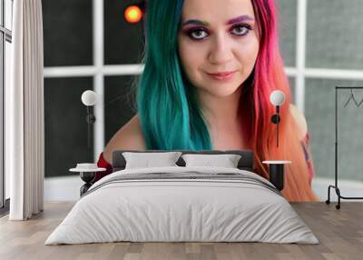 Close-up portrait of a pretty girl with multi-colored hair and make-up on a colored background. Stands with a smile in various poses in the studio. Wall mural