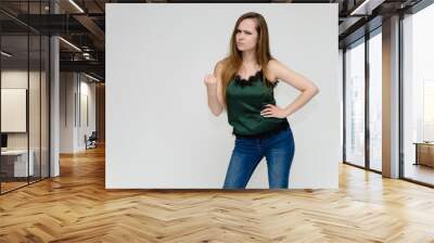 Concept portrait above the knee of a pretty girl, a young woman with long beautiful brown hair and a green t-shirt and blue jeans on a white background. In studio in different poses showing emotions. Wall mural