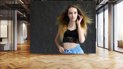 Photograph of a portrait of a beautiful girl woman with long dark flowing hair, happy life on a dark gray background. She is standing directly in front of the camera in various poses and smiling. Wall mural