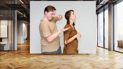 Portrait below the belt on a white background pretty young brunette woman in a brown dress and a young man in a brown shirt. Standing in different poses, talking, showing emotions. Wall mural