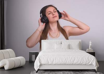 portrait of a beautiful brunette girl on a white background in headphones listening to music Wall mural