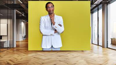 Portrait of a young African American man with short haircuts and a white-toothed smile in a white jacket on a yellow background. Standing and talking right in front of the camera. Wall mural