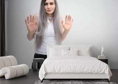 Studio portrait on the waist of a pretty manager girl with long beautiful hair in a white T-shirt and black shorts on a white background. He stands straight, smiles, shows with his hands. Wall mural