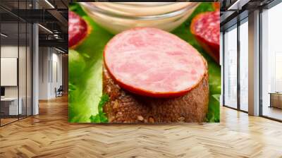 Several sandwiches with sausage and salami and sauce on a plate, close up Wall mural