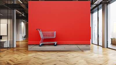 Shopping cart on the background of a red wall, copy space. Wall mural