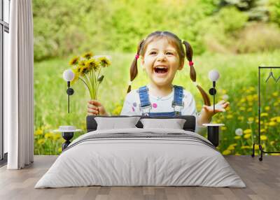 a beautiful girl with two tails holds a bouquet of dandelions and laughs Wall mural