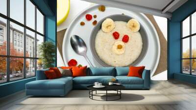 Funny cute kids childrens baby's healthy breakfast lunch oatmeal porridge in bowl look like bear face decorated with apple, banana, dried berry fruits. dessert food art on white wooden table Wall mural