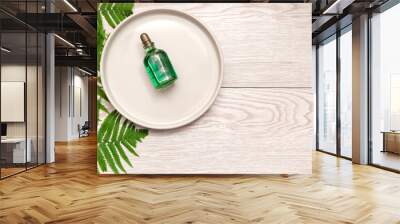 Natural cosmetics perfume essential oil serum in green glass bottle with dropper on plate, wooden background with green fern branches with copy space. eco ecology beauty concept. Wall mural