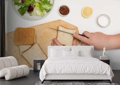 woman chef is cooking, making diet homemade caesar salad, step by step instruction. Step 1 - cutting bread for frying croutons and adding to salad leafs Wall mural