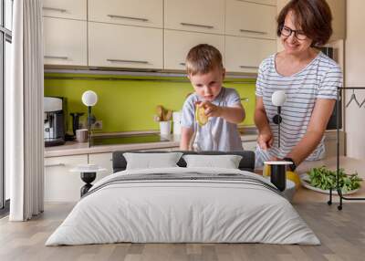 Adult woman is preparing lemonade with her son. Cold drink. Summer heat. Vegetarian food concept. Wall mural