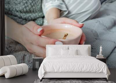 Young woman sits on a bed in the bedroom and drinks hot coffee. Defocus. Wall mural