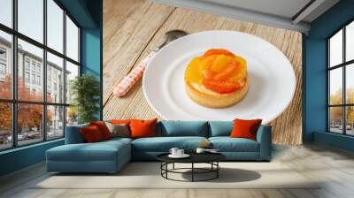 Tartlet with tangerine and grapefruit lies on a plate on a wooden table. beautiful dessert Wall mural