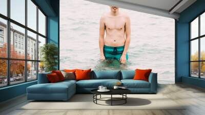 a young guy is swimming in the blue clear water of the ocean Wall mural