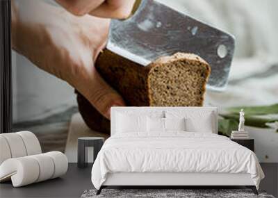 cutting with a knife freshly baked bread on a wooden Board Wall mural