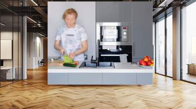 A woman cooking vegetarian food in a modern kitchen in gray tones. Blurry motion Wall mural