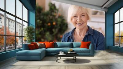 Cheerful elderly woman standing in the kitchen Wall mural