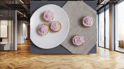 Three cupcakes with pink creme on a white oval plate. two cupcakes on a napkin Wall mural