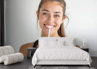 A female athlete drinks a milkshake and smiles on a white background Wall mural