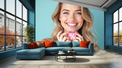 A smiling young beautiful woman holds a 3D percentage sign in her hands Wall mural