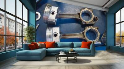 Two pistons assembled with connecting rods lie on a blue desktop Wall mural