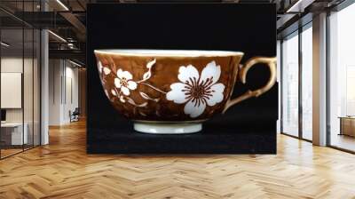 Elegant brown tea cup with white floral design on a dark background Wall mural