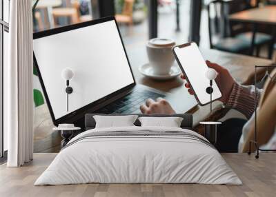 A person is holding a cell phone in front of a laptop Wall mural