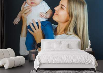 A smiling young mother holds her newborn son in her arms. Happy mother. Son and mother. Concept of happy motherhood Wall mural