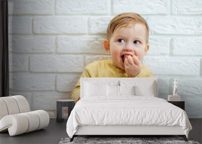 Cute smiling kid eating one fresh juicy tangerine Wall mural