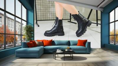 Slender female legs in leather black boots. Young woman in stylish leather shoes Wall mural