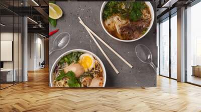 a still life of Asian ramen soups and a photo on a gray background in craft dishes. concept: food delivery, street food Wall mural