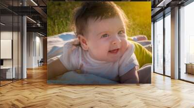 the child lies on the grass, a six-month-old girl Wall mural