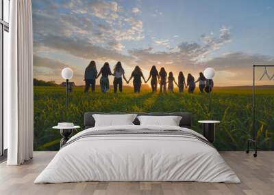 A group of girls walk towards the sun at sunset holding hands. Wall mural