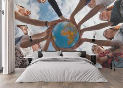 Earth conservation concept. 11 girls hug the earth globe with their hands. Wall mural